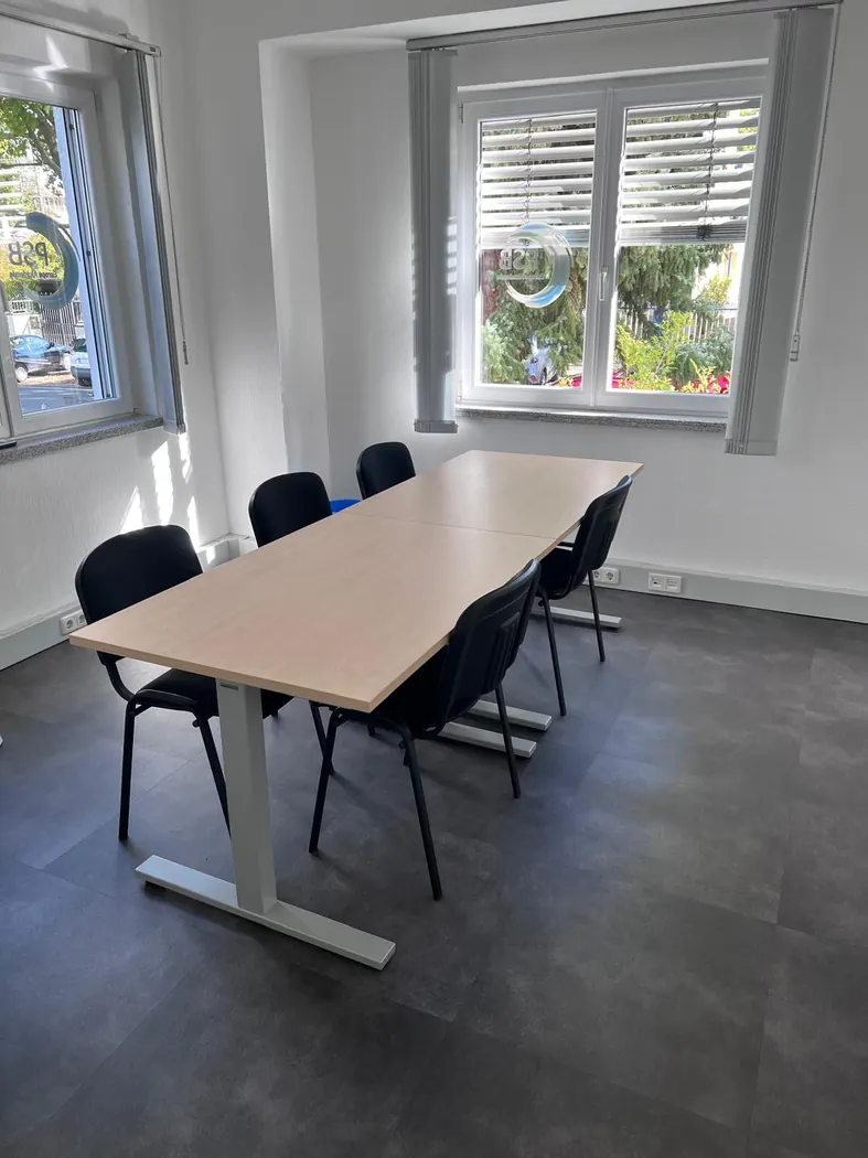 Besprechungsraum mit Tisch und schwarzen Stühlen